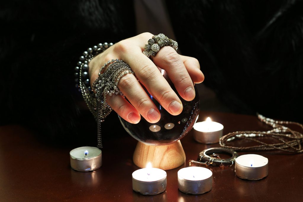 Hand with rings held over a crystal ball